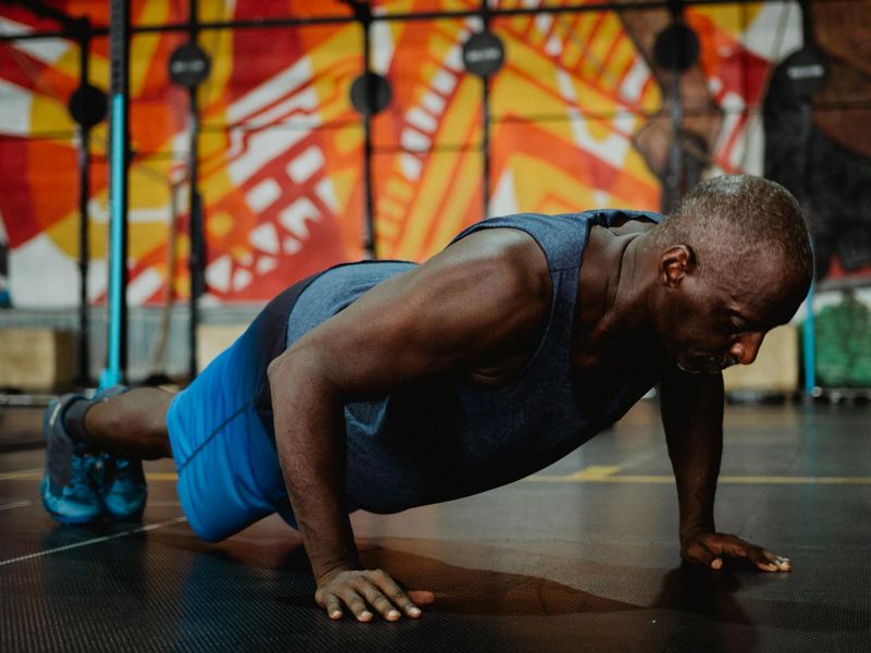 Athletic man performing a push up in a gym.